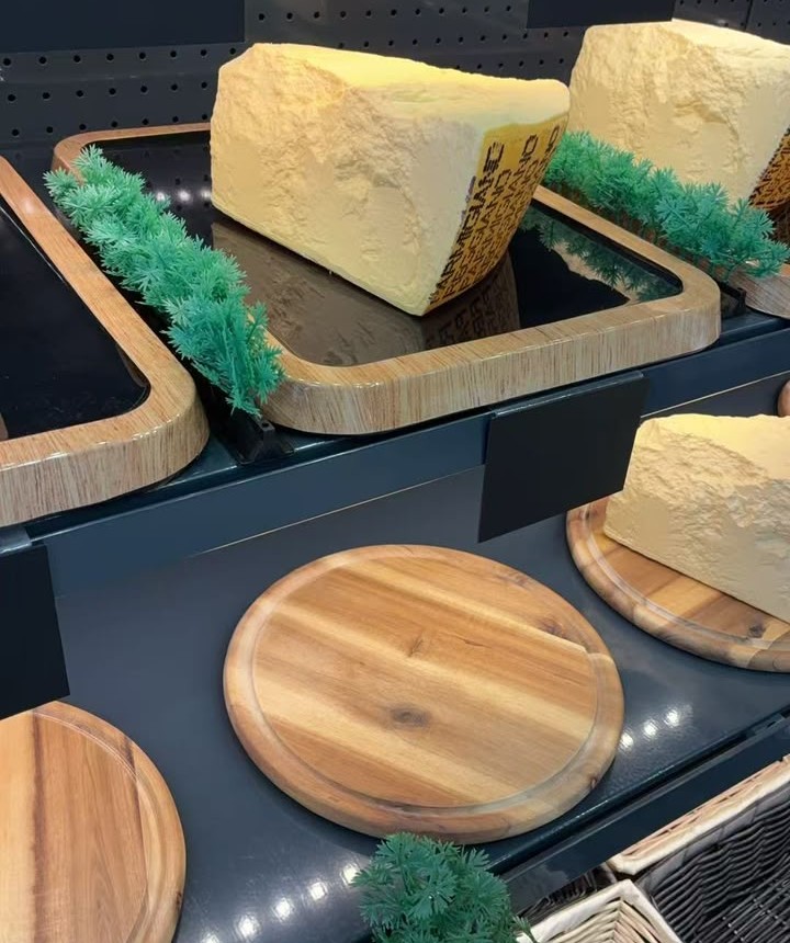Grüner Deko-Streifen am Holzrand einer Schale mit Käse in der Vitrine